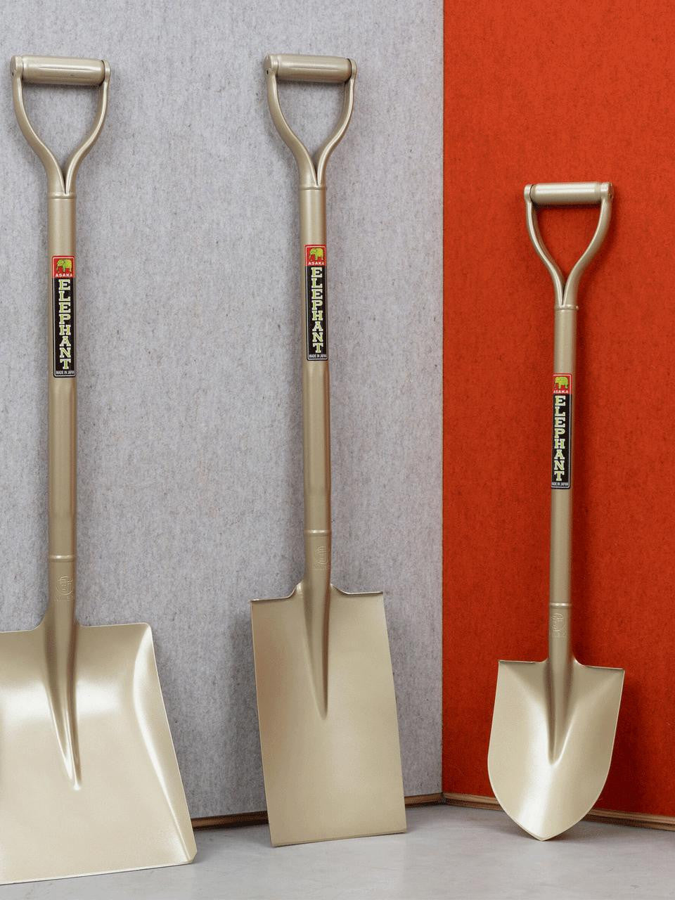 Small golden shovel by Elephant Tools with a wooden handle and metal scoop, ideal for gardening or outdoor tasks.