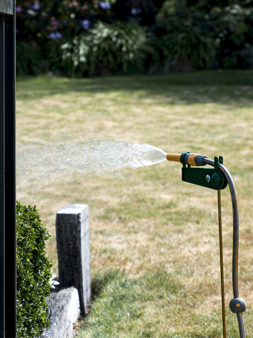 Dugard Hose Holder with garden hose coiled around wall-mounted bracket — Bugg