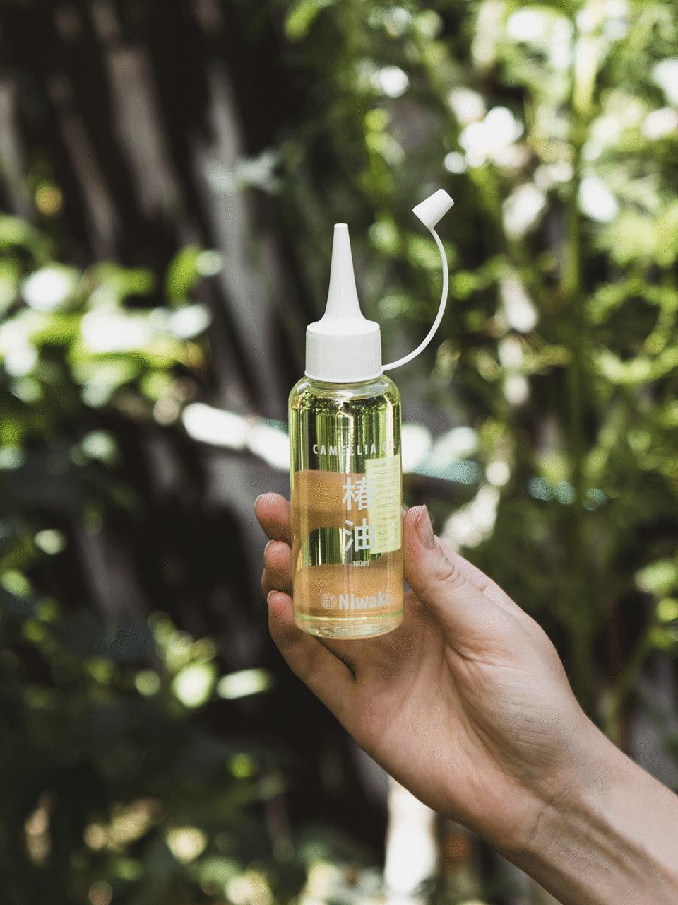 Botanical bottle of Kamaki Camellia Oil with a white label, showcasing the natural oil product on a neutral background.