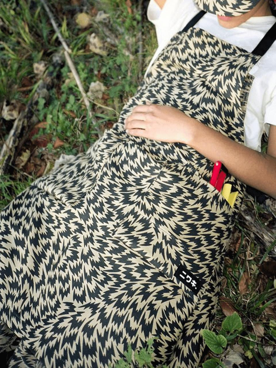 Niwaki Eley Kishimoto X Flash Apron with adjustable straps and colorful print, designed for gardening and outdoor work.