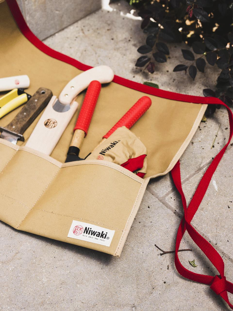 Niwaki tool roll with multiple pockets for garden tools, made of durable fabric, rolled up for easy storage and transport.