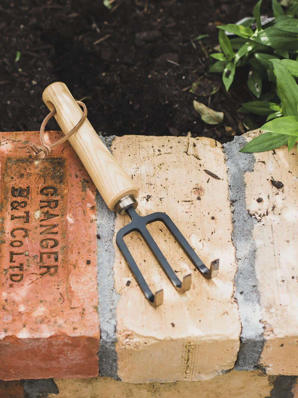 Niwaki Moku Cultivator with wooden handle and metal tines for garden soil cultivation and aeration.