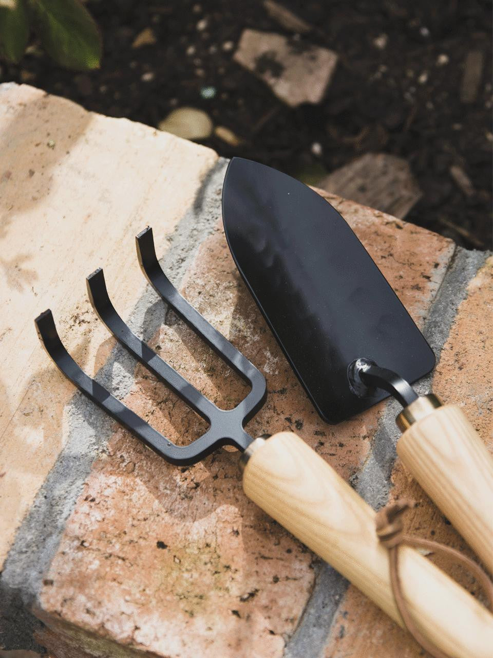 Niwaki Moku Cultivator with wooden handle and metal tines for aerating and cultivating garden soil.