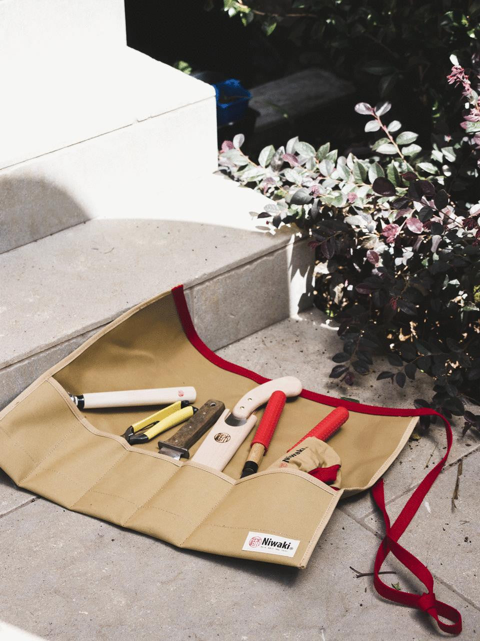 Niwaki tool roll with multiple compartments for gardening tools, made of durable fabric, on a neutral background.