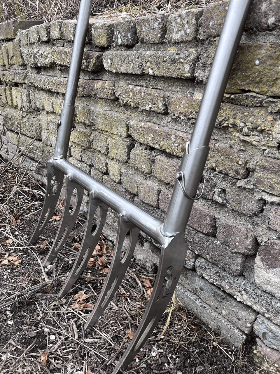Sneeboer broadfork with wooden handles and sturdy metal tines for aerating and loosening soil in gardening tasks.