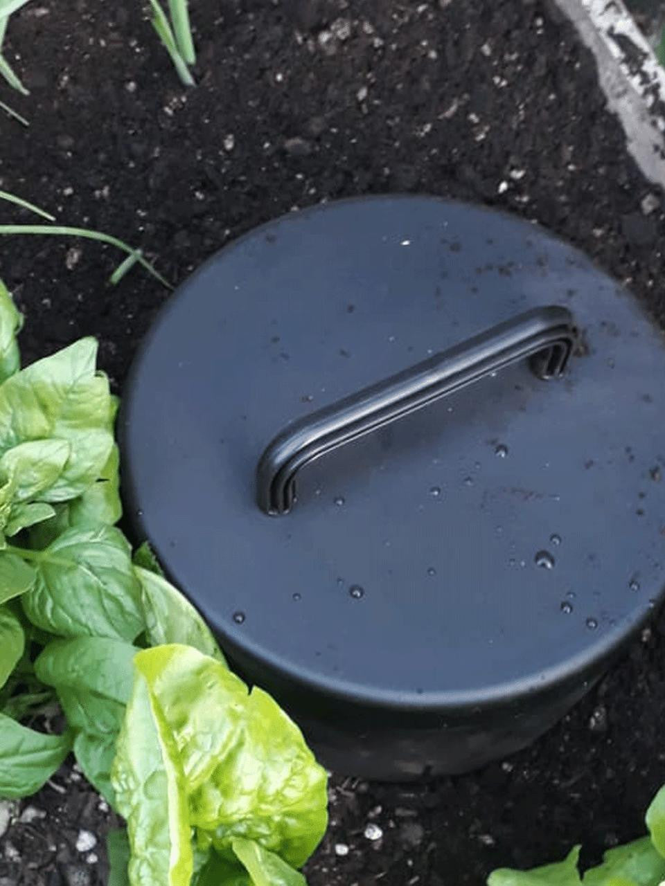 In-ground composter by Tui Garden Products showing a brown compost bin installed in the soil for organic waste recycling.